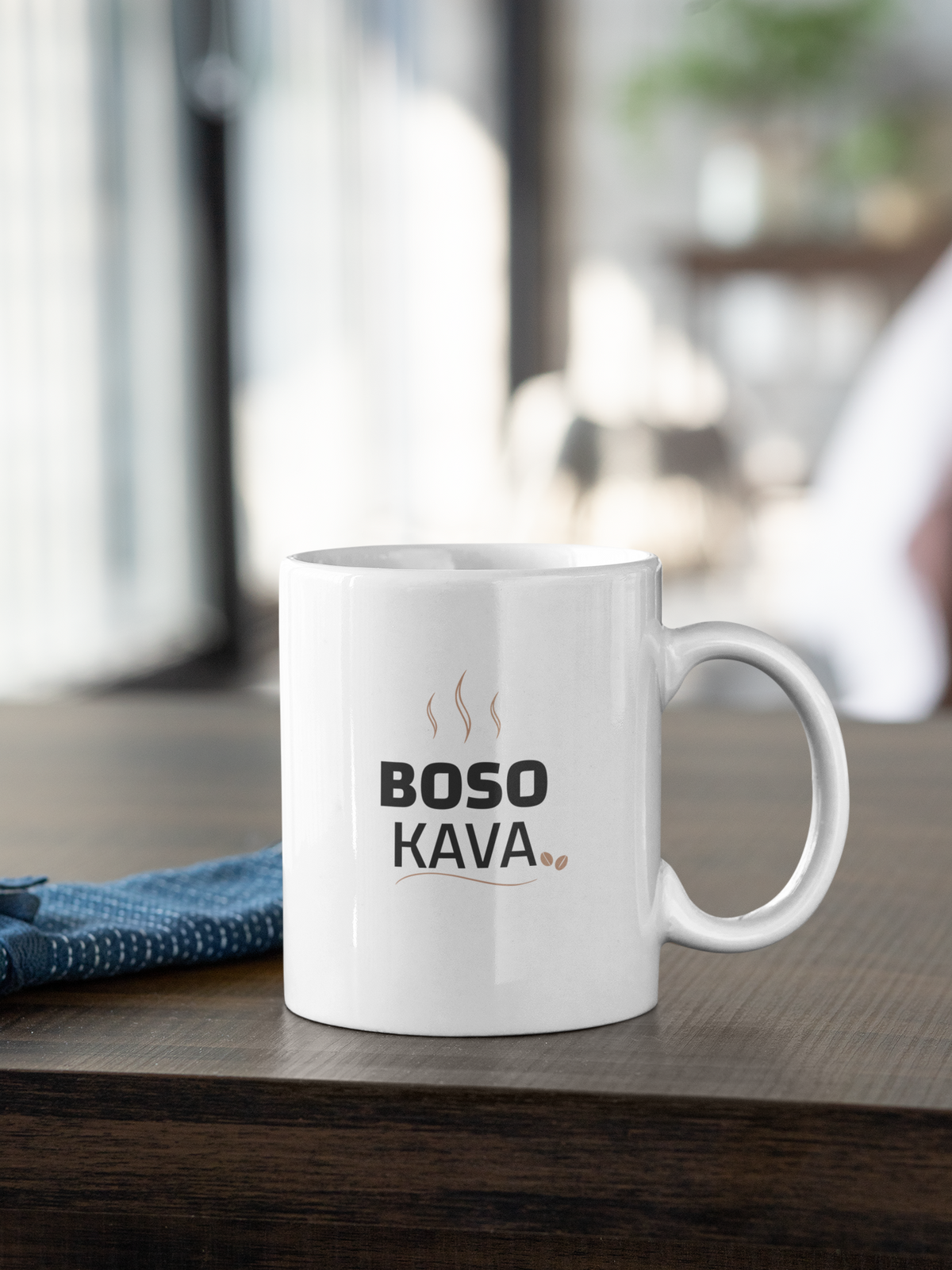Baltas puodelis su užrašu "BOSO KAVA" su pupelėmis.